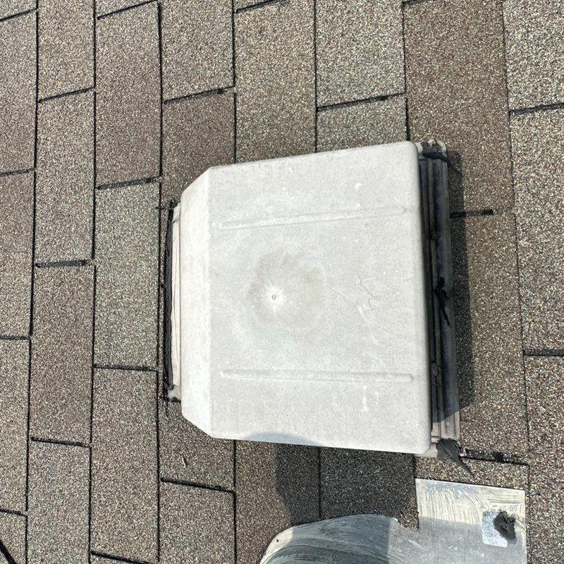 Roof vent with hail impact dent on asphalt shingles Roof vent with hail impact dent on asphalt shingles