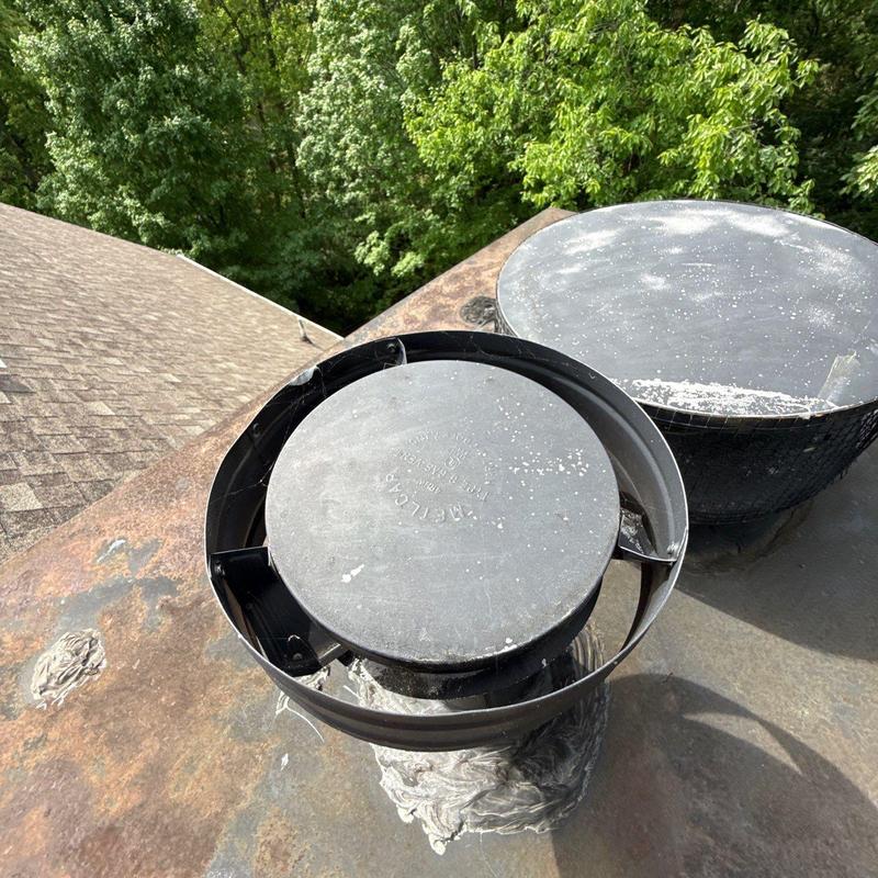Roof vent caps on metal chimney flashing with sealant