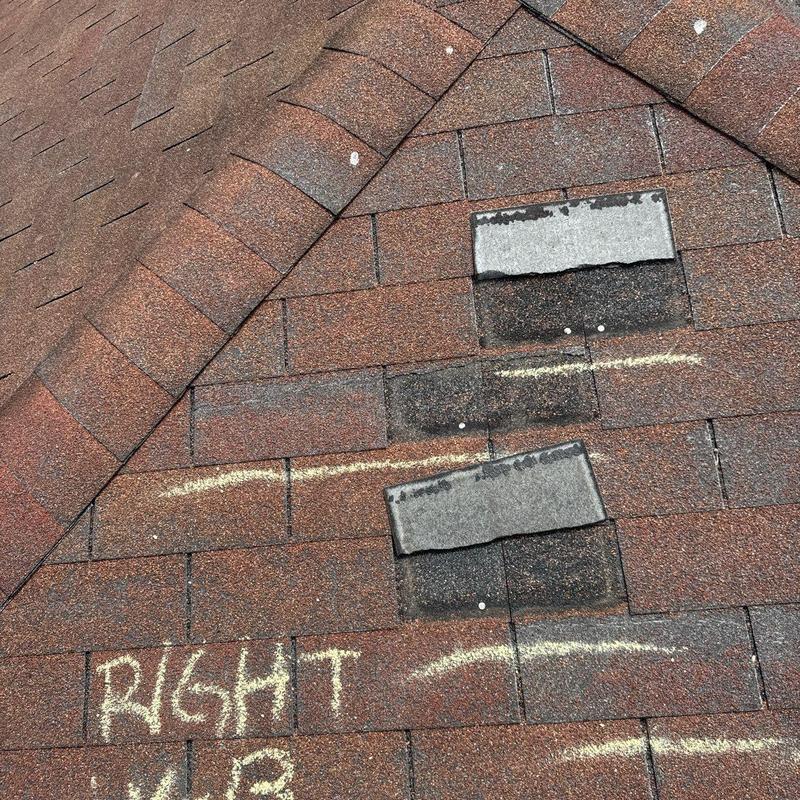 Asphalt shingles with impact damage marked for repair