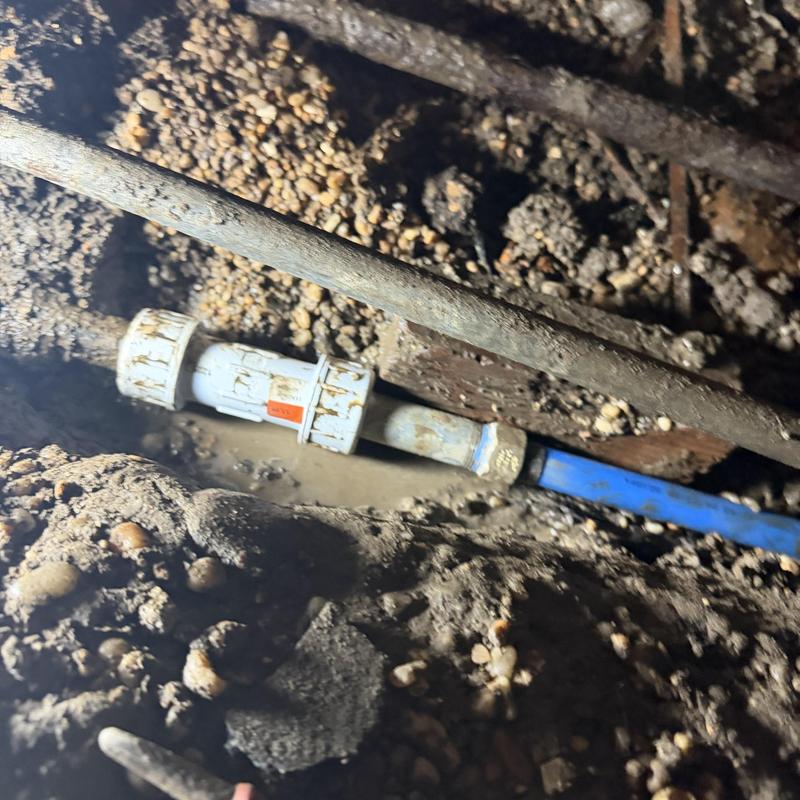 Water supply line with connector under house in dirt Water supply line with connector under house in dirt