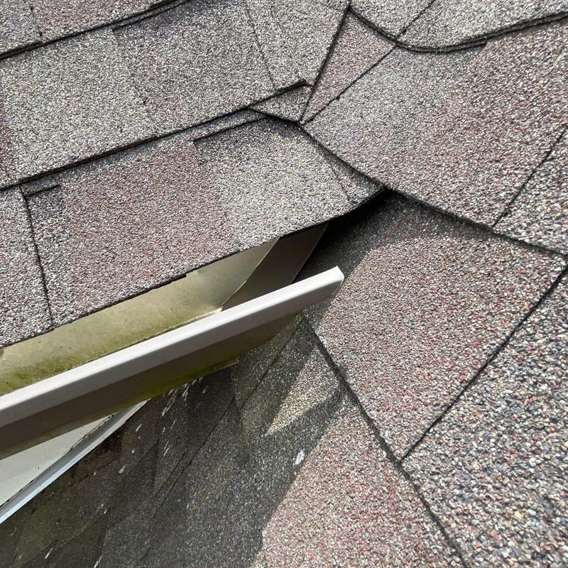 Roof shingles with damage near metal flashing gap