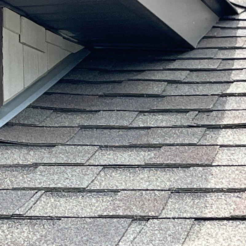 Roof shingles showing wear and storm damage near flashing