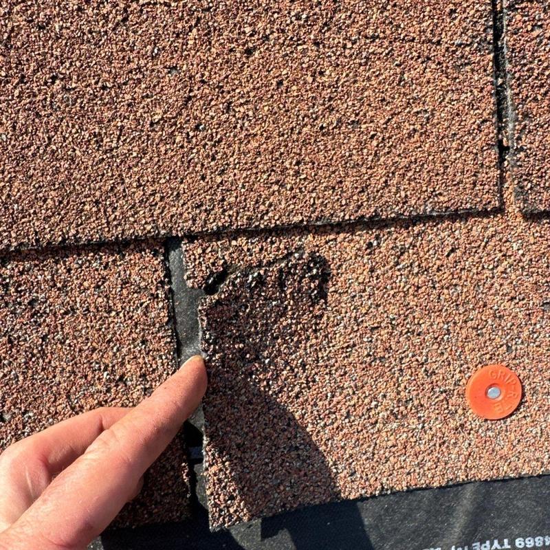 Roof shingle lifted to inspect hail damage and wear