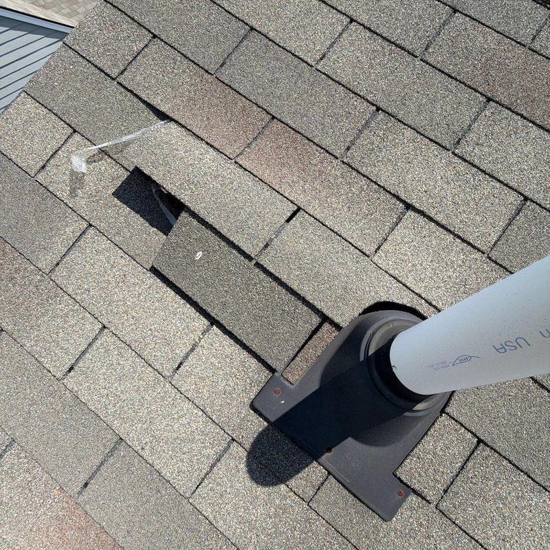 Roof shingles with missing and damaged pieces near vent pipe