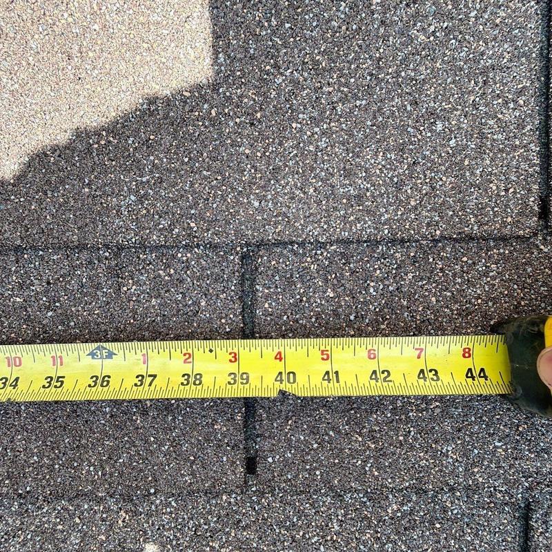 Roof shingles with tape measure for damage assessment