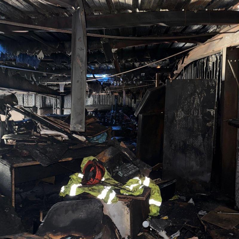 Warehouse ceiling fire damage with debris and gear