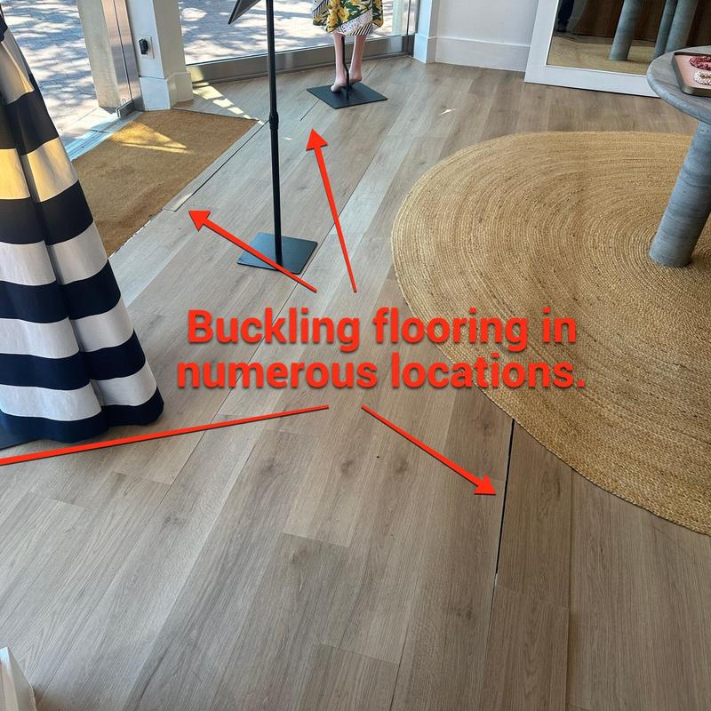 Wooden flooring with buckling near entryway and rug Wooden flooring with buckling near entryway and rug