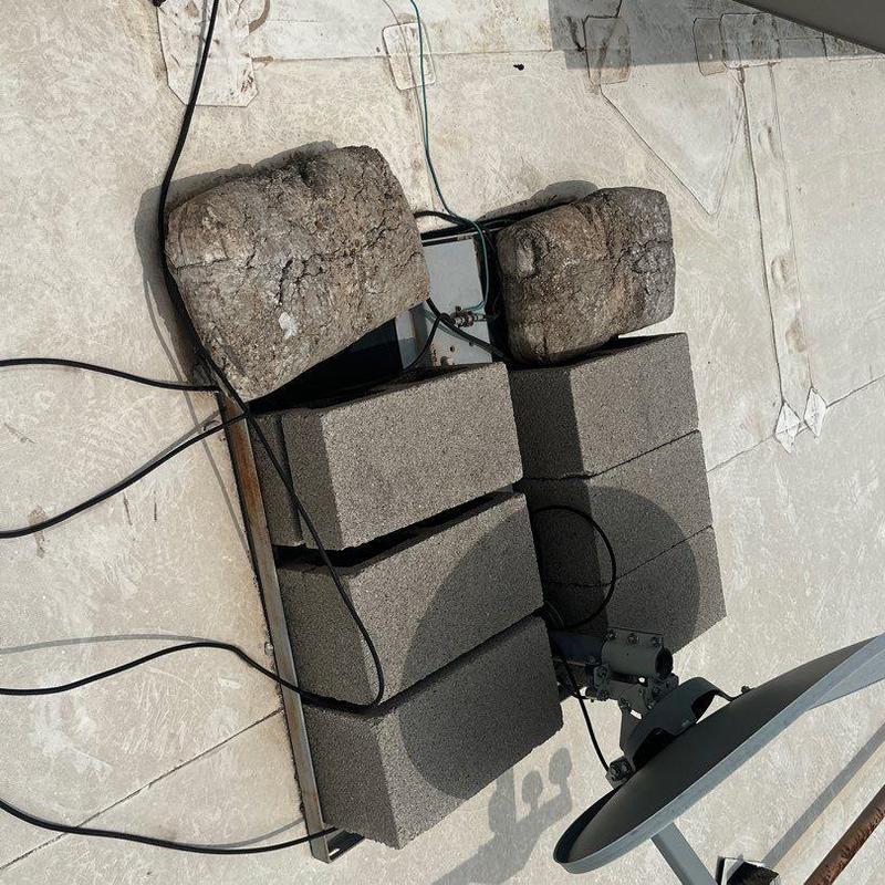 Satellite dish secured with cinder blocks on roof Satellite dish secured with cinder blocks on roof