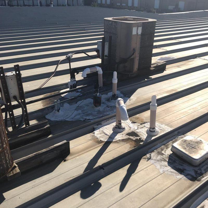Metal roof with sealed pipe penetrations and HVAC unit