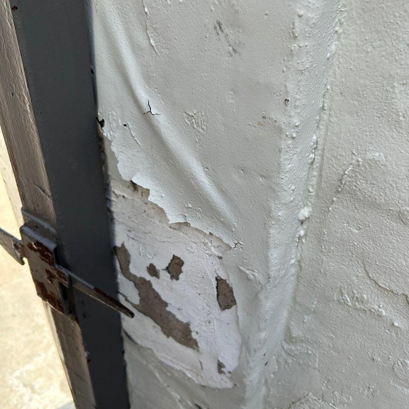 Stucco corner with peeling and cracking damage Stucco corner with peeling and cracking damage