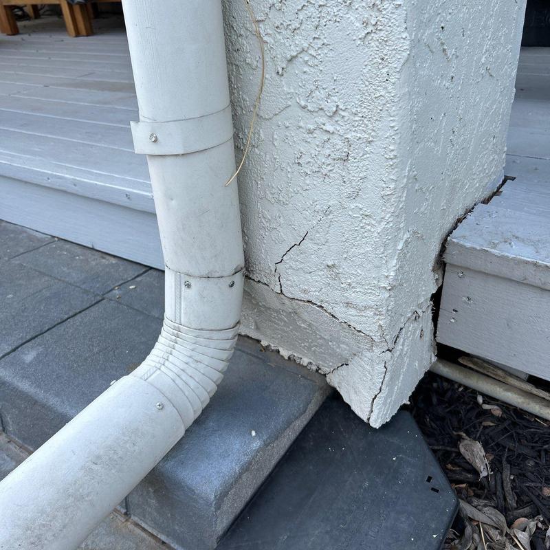 Stucco corner cracks by downspout at porch base Stucco corner cracks by downspout at porch base