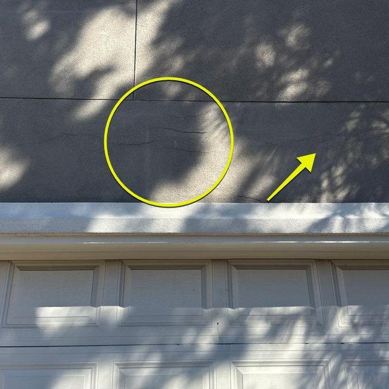Stucco wall cracks above garage door with markings Stucco wall cracks above garage door with markings