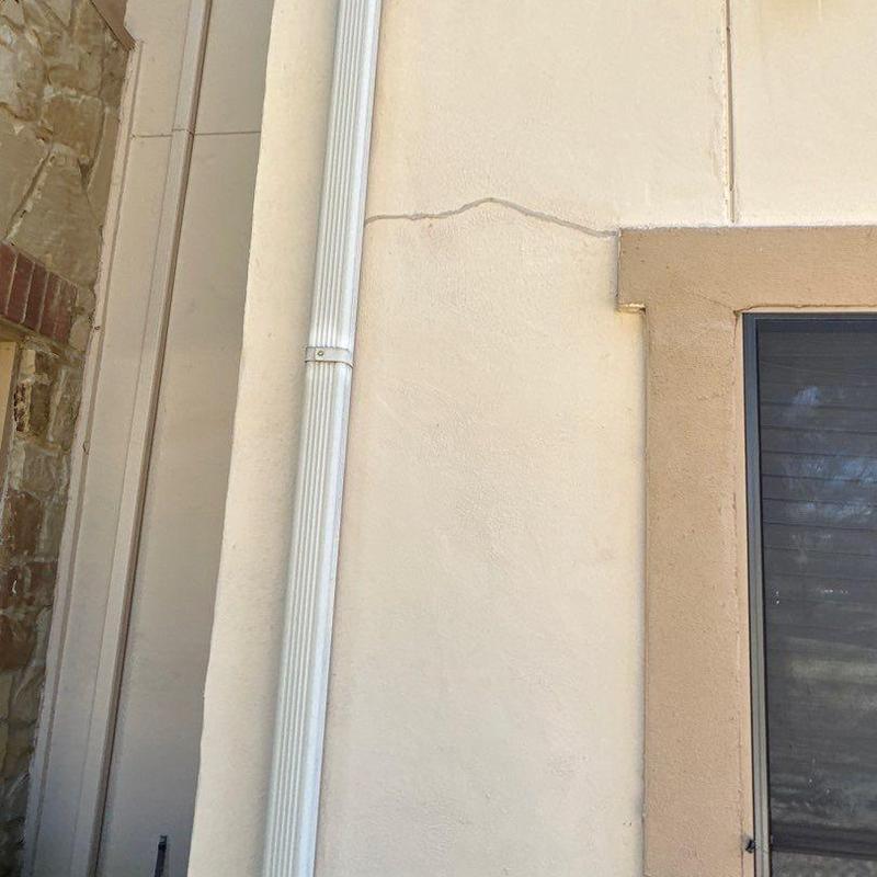 Stucco exterior wall with visible cracking near window Stucco exterior wall with visible cracking near window