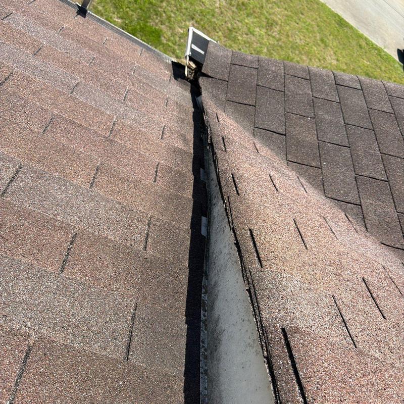 Roof valley with asphalt shingles and gutter downspout