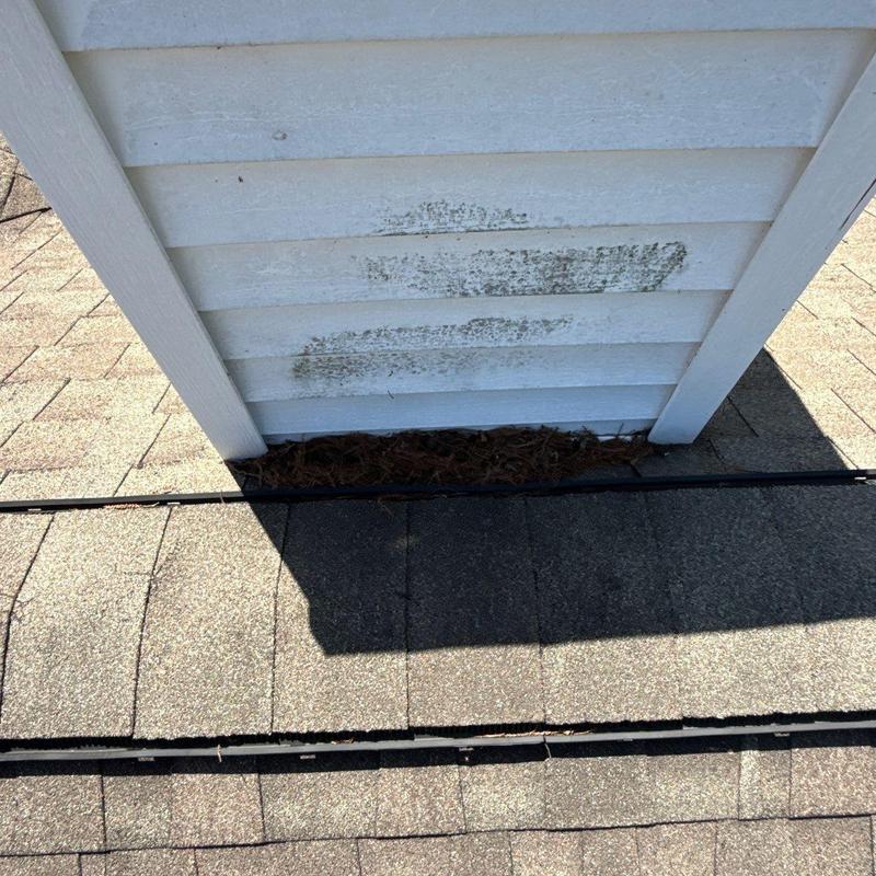 Roof shingles near chimney base with mildew stains