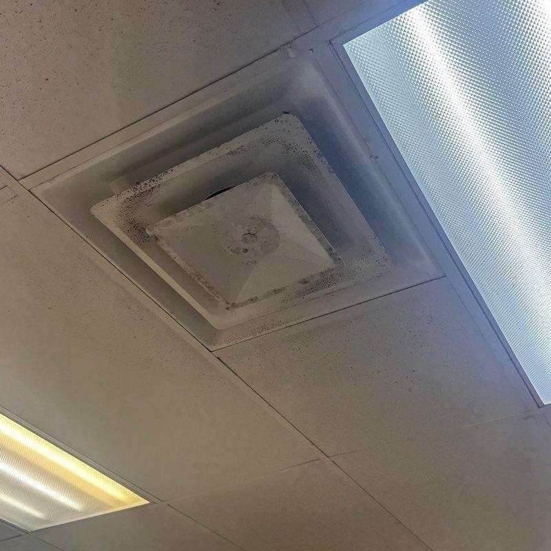 Ceiling HVAC vent with dust buildup near fluorescent lights Ceiling HVAC vent with dust buildup near fluorescent lights