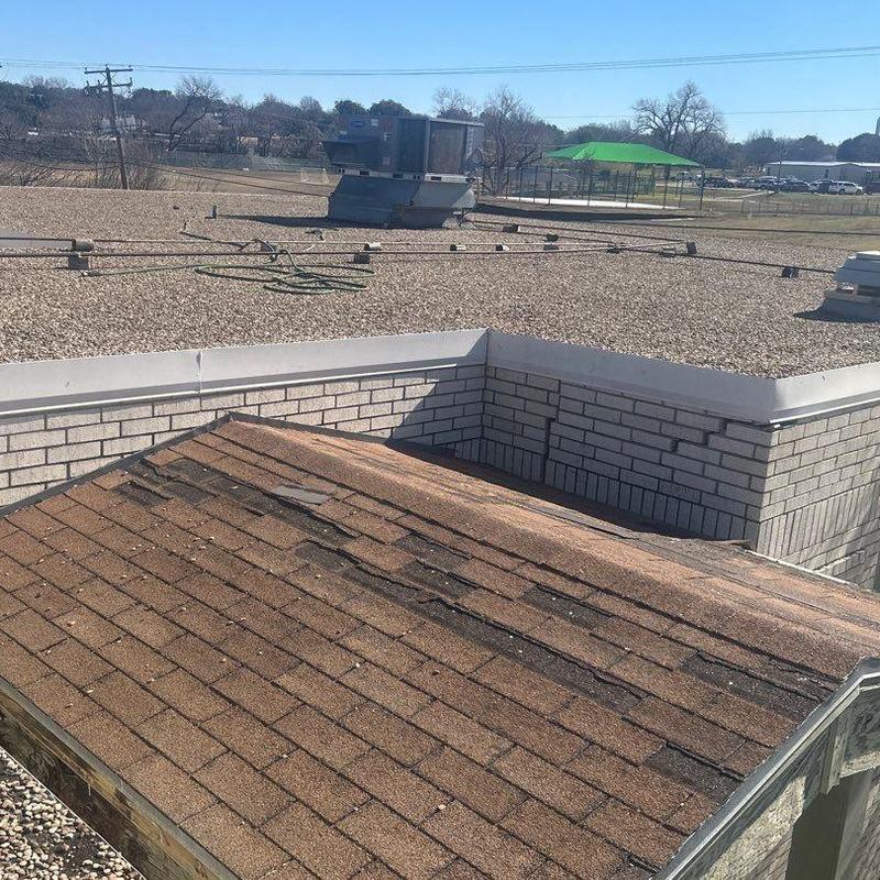 Damaged shingle roofing section on building roof Damaged shingle roofing section on building roof