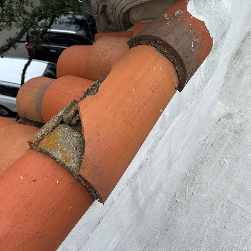 Clay tile roof ridge with cracked tiles and mortar damage Clay tile roof ridge with cracked tiles and mortar damage