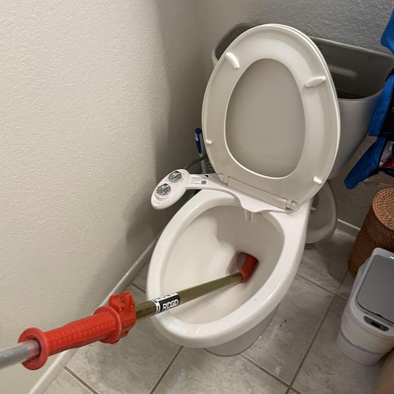 Toilet auger clearing clog in hallway bathroom toilet
