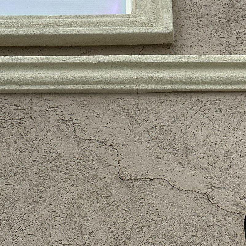 Stucco wall cracks near window trim and stonework Stucco wall cracks near window trim and stonework
