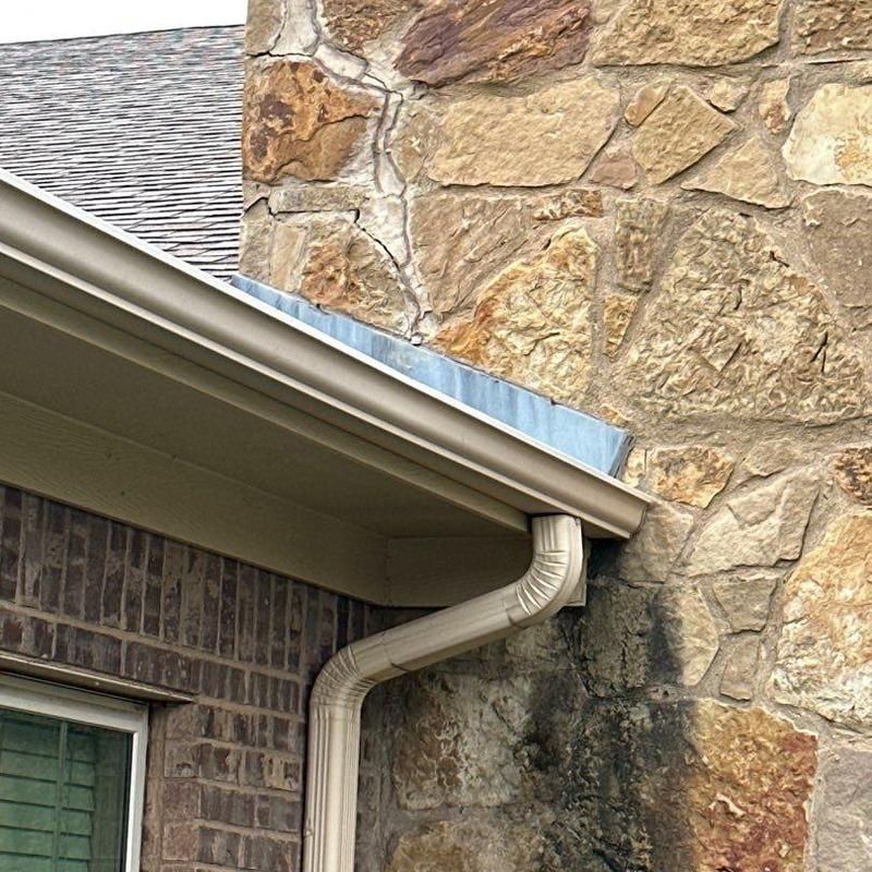 Stone veneer masonry near roofline with gutter system Stone veneer masonry near roofline with gutter system