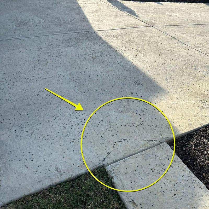 Concrete driveway with visible crack and patch area Concrete driveway with visible crack and patch area