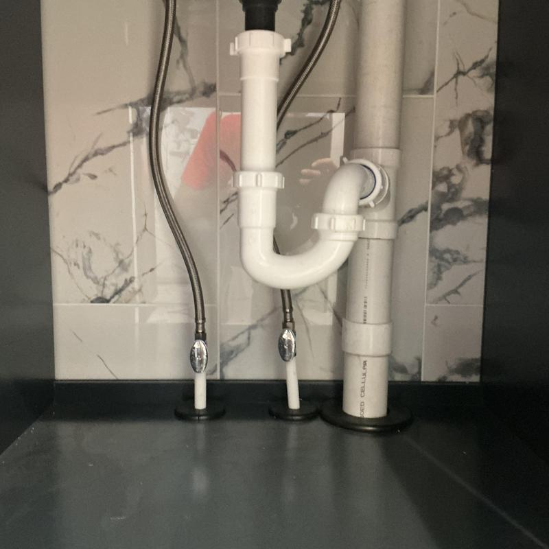 Bathroom sink drain pipes and water supply lines under cabinet