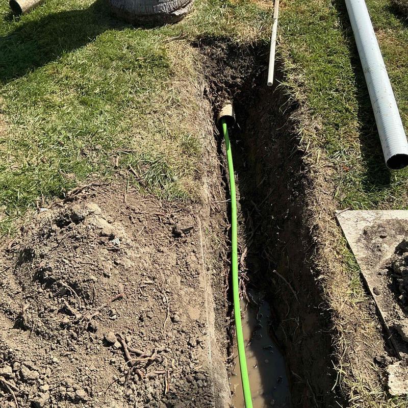 Area drain line hydro jetting with green hose in trench