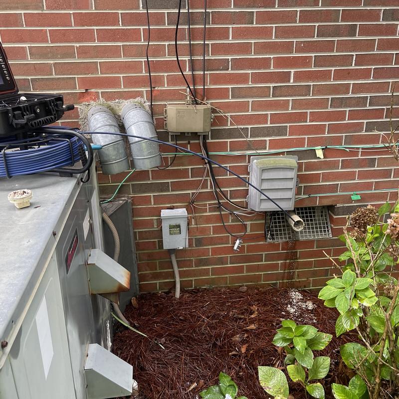 Sewer pipe with snake cable cleaning blockage near brick wall Sewer pipe with snake cable cleaning blockage near brick wall
