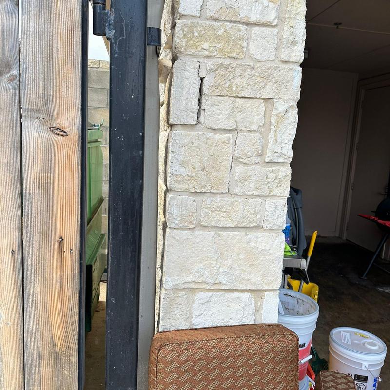 Stone wall with cracks near trash enclosure gate Stone wall with cracks near trash enclosure gate