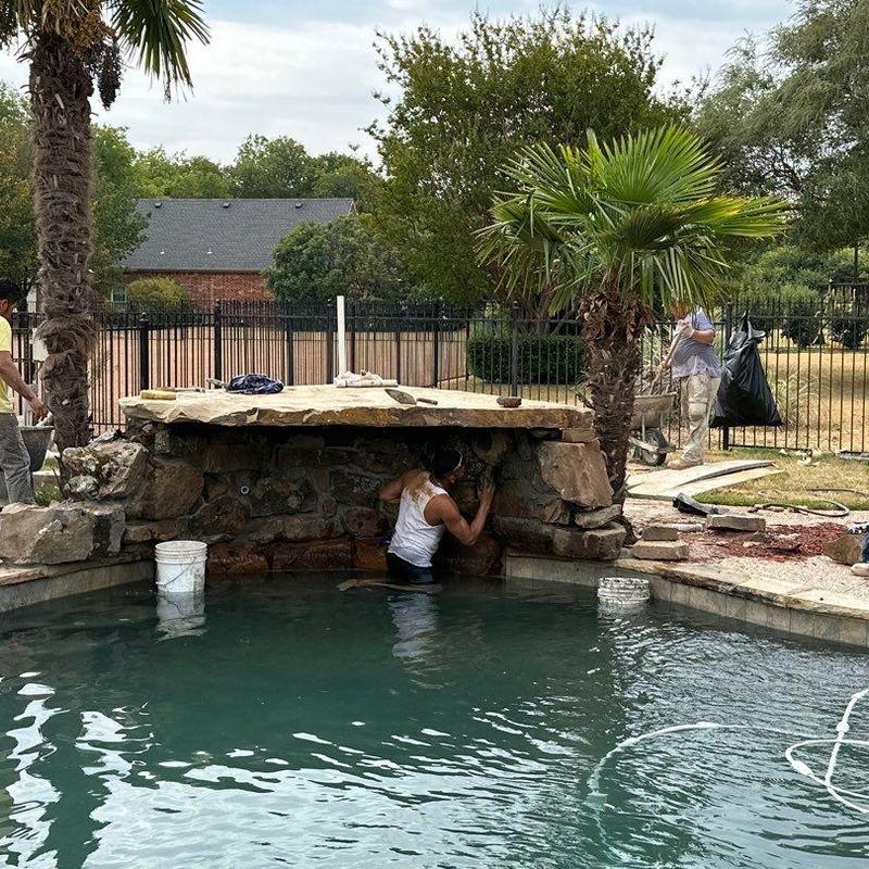 Natural stone waterfall repair beside pool Natural stone waterfall repair beside pool