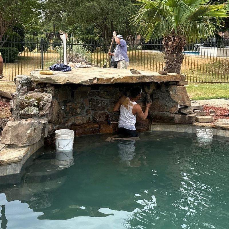 Natural stone waterfall repair beside pool Natural stone waterfall repair beside pool