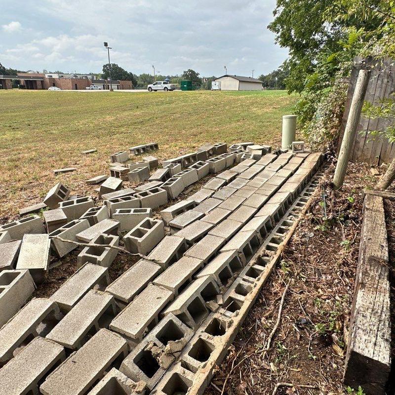 Block wall sections stacked beside damaged boundary wall Block wall sections stacked beside damaged boundary wall