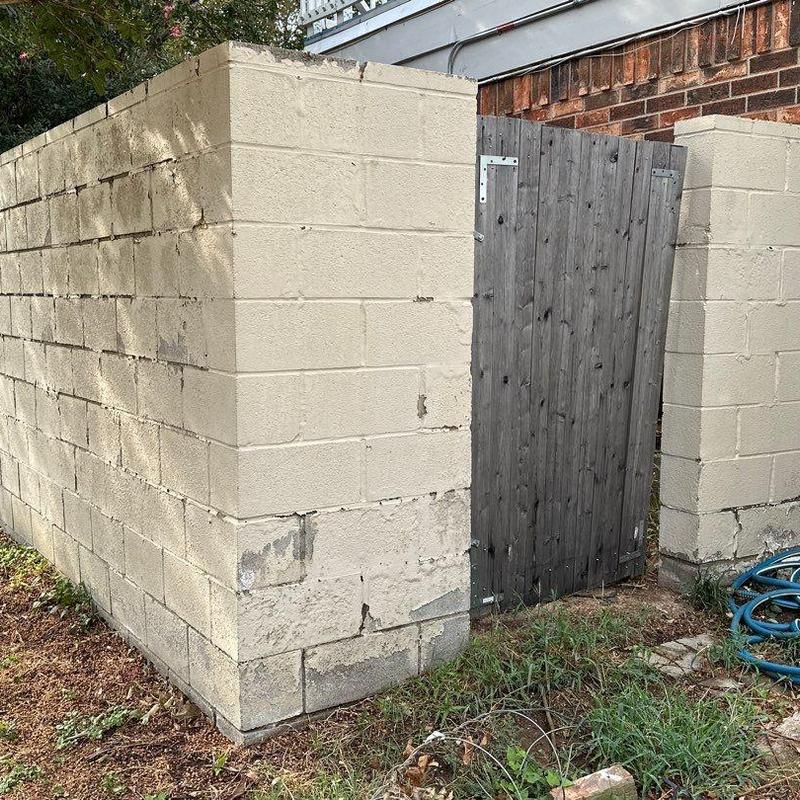 Block wall with damaged sections and wooden gate Block wall with damaged sections and wooden gate