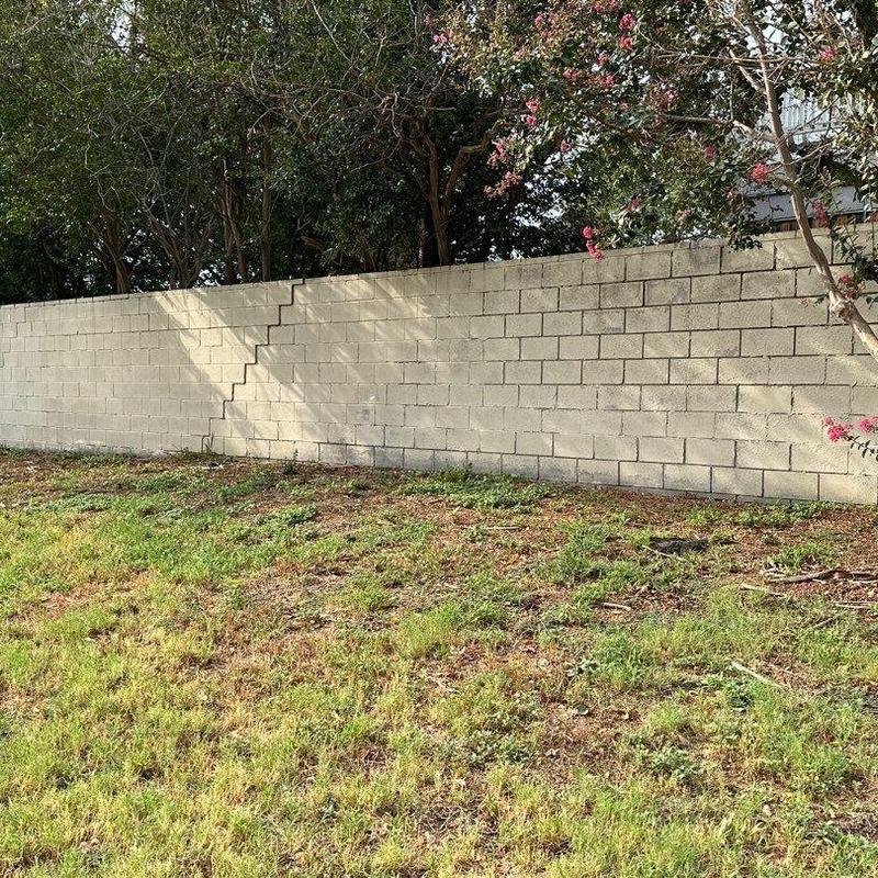 Block boundary wall with visible diagonal crack outdoors Block boundary wall with visible diagonal crack outdoors
