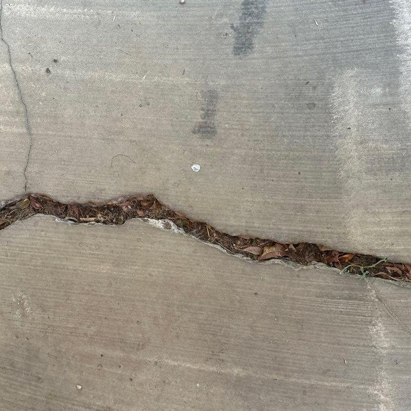 Sidewalk concrete joint with large crack and debris Sidewalk concrete joint with large crack and debris