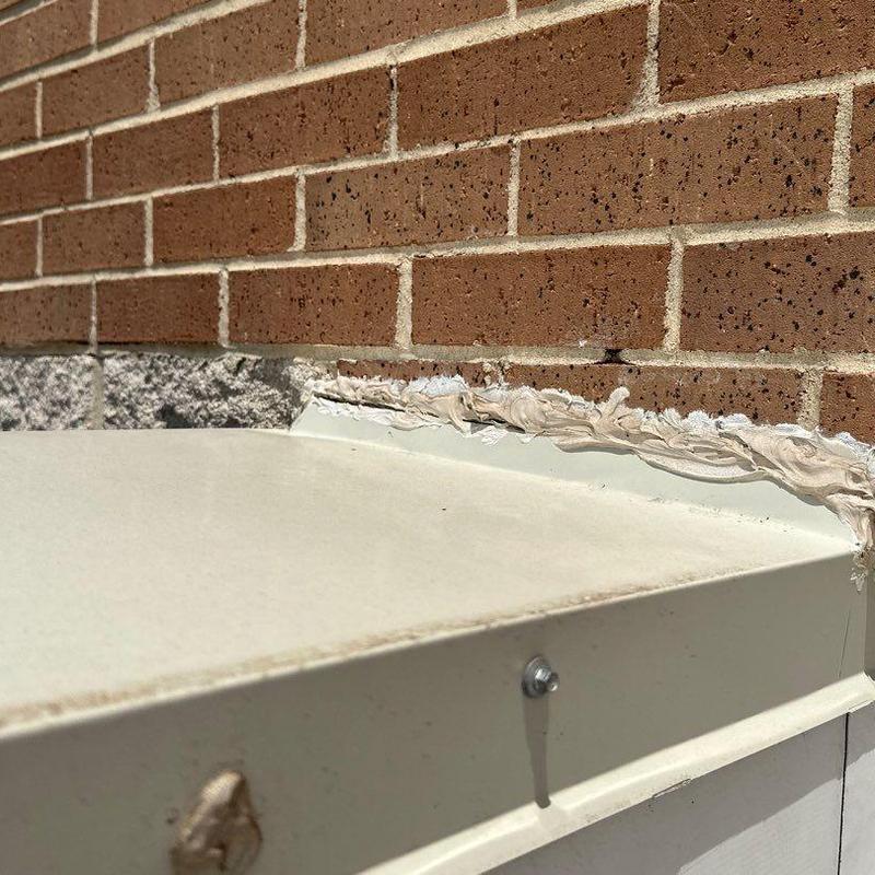 Concrete roof seam with sealant repair against brick wall Concrete roof seam with sealant repair against brick wall