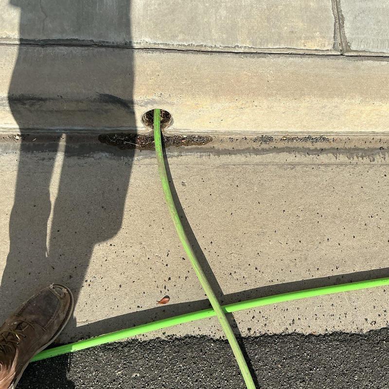 Area drain hydro-jetting hose inserted in curb drain opening