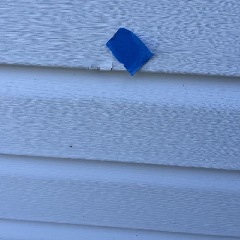 Vinyl siding with crack marked by blue tape