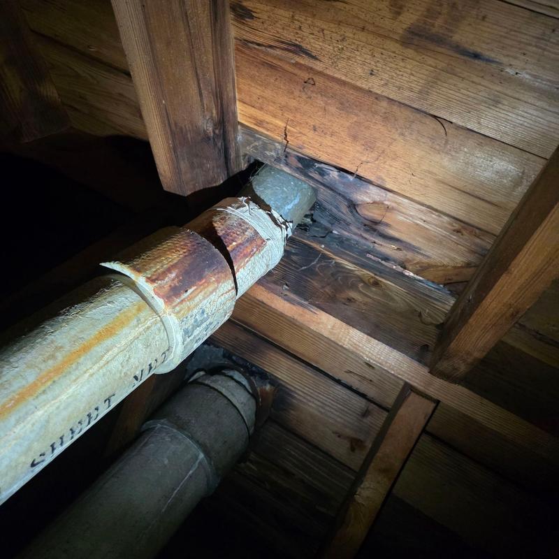 Rusty vent pipe with wood rot and water damage