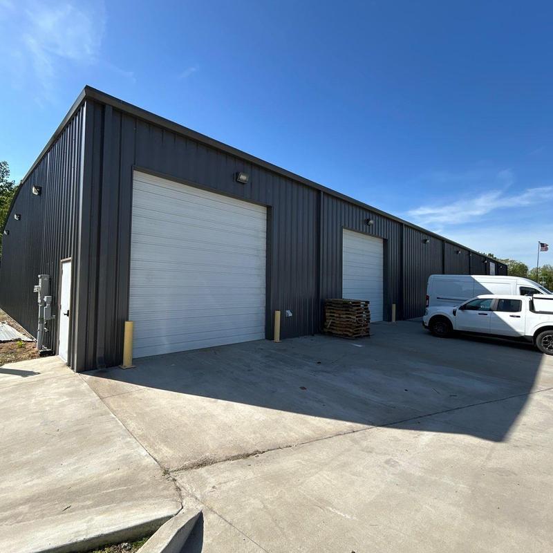 Metal building exterior with roll-up doors and parked vans