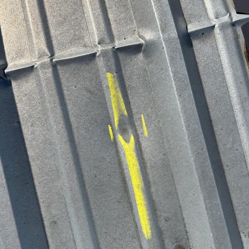 Metal roof panel with hail damage marked in yellow