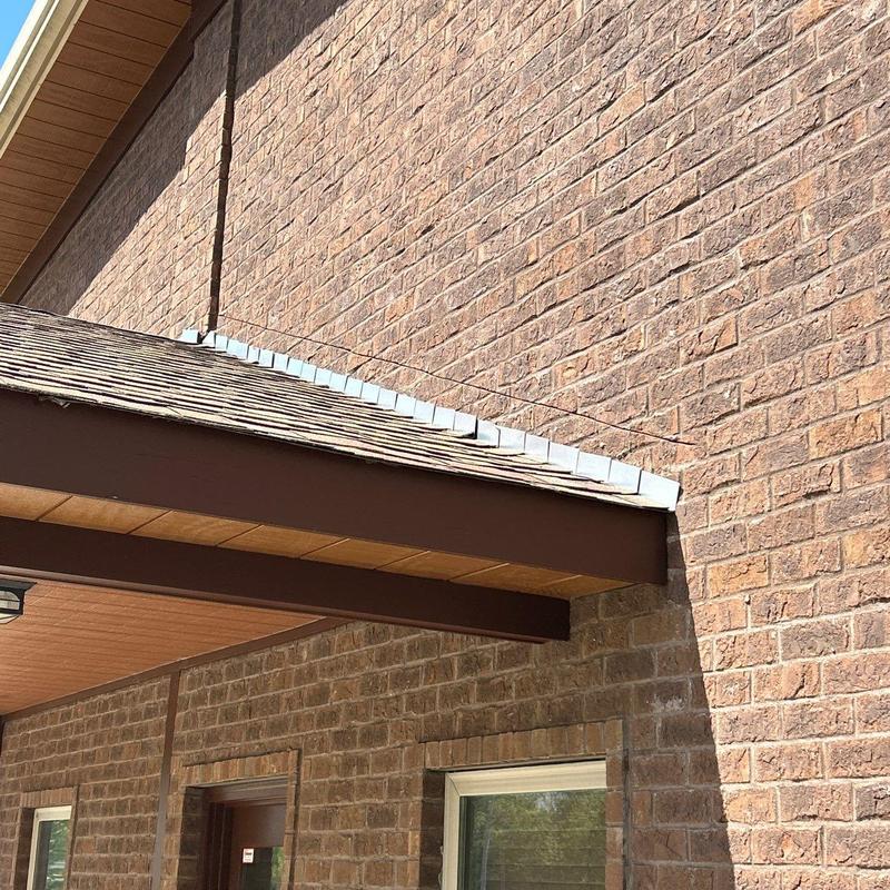 Asphalt shingle roof with metal flashing on brick wall