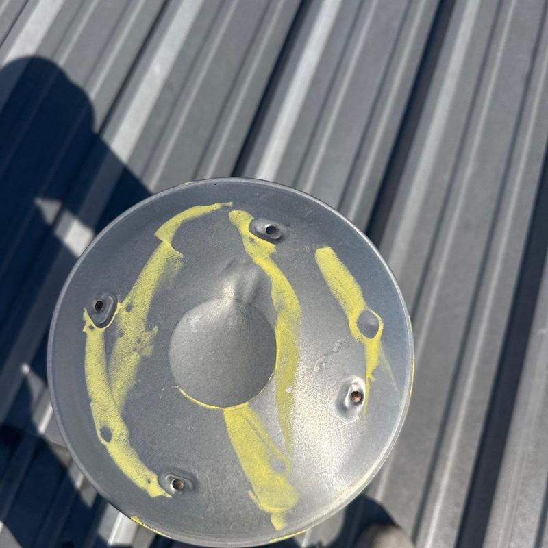 Metal roof vent with hail damage marked in yellow paint