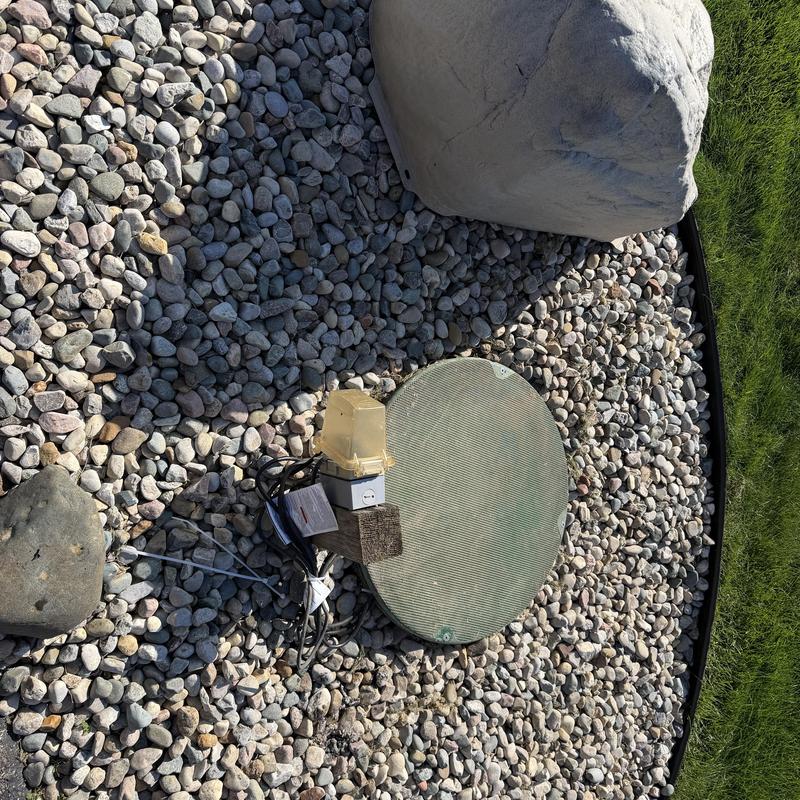 Sewage pump system cover with alarm sensor on rocks