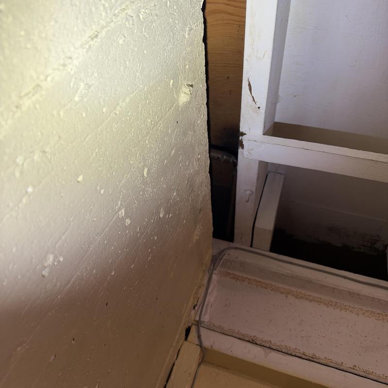 Wall junction with exposed plumbing pipe and cabinet frame