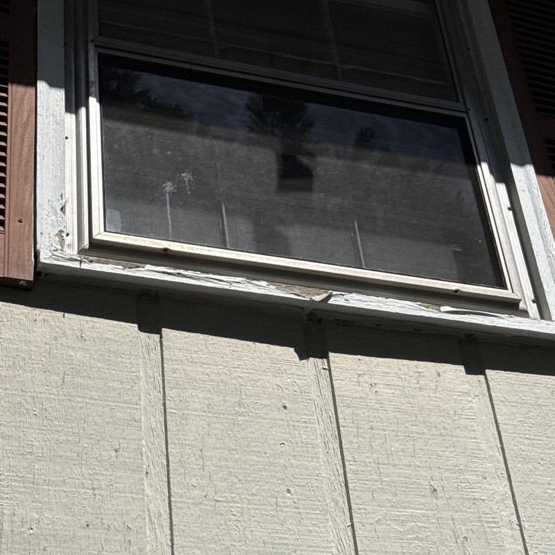 Window frame with peeling paint and worn siding
