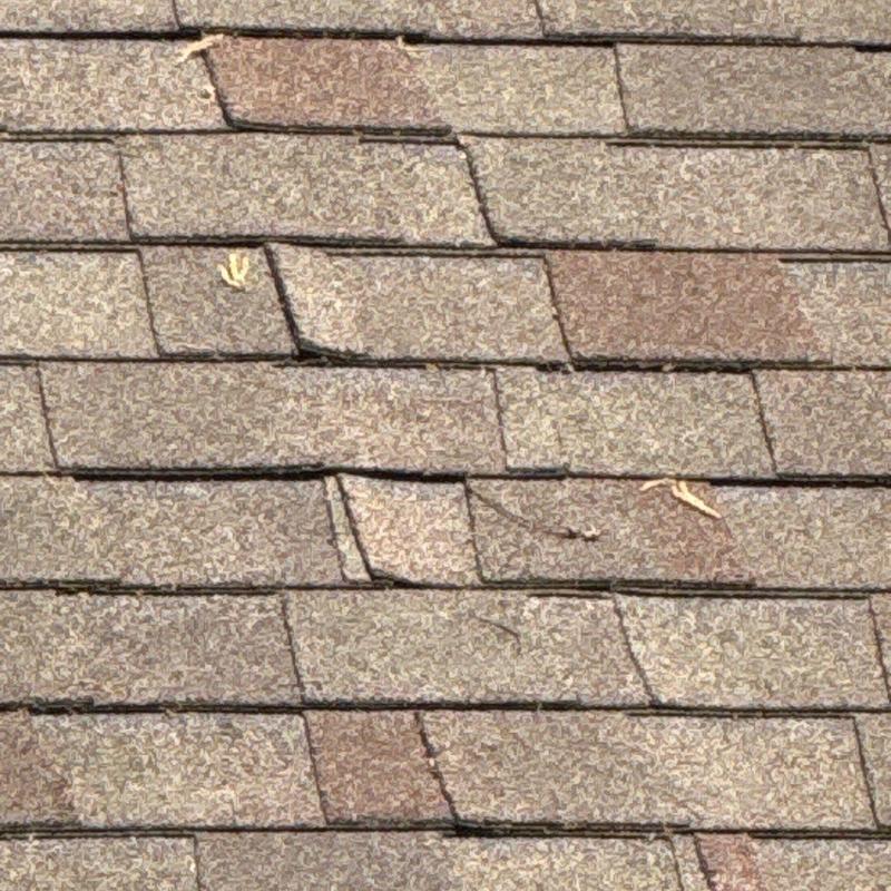 Asphalt shingles with visible cracking and damage