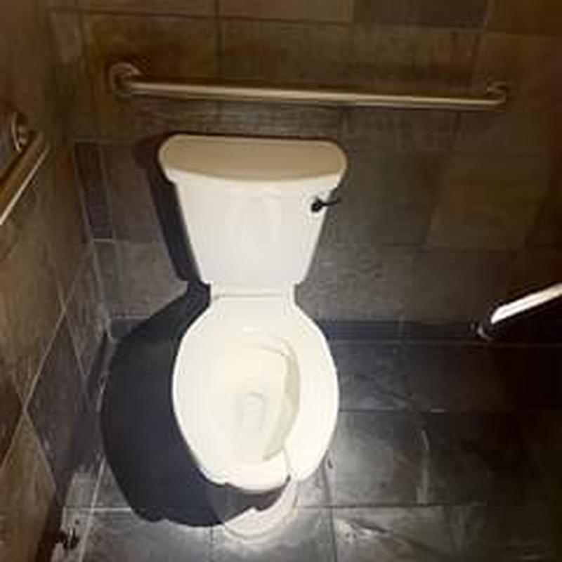 Toilet with tank and seat in tiled restroom