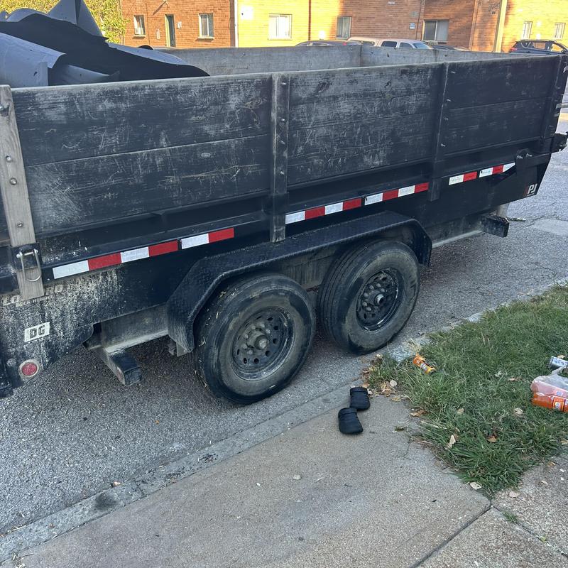 Dump trailer with flat tire by roadside curb